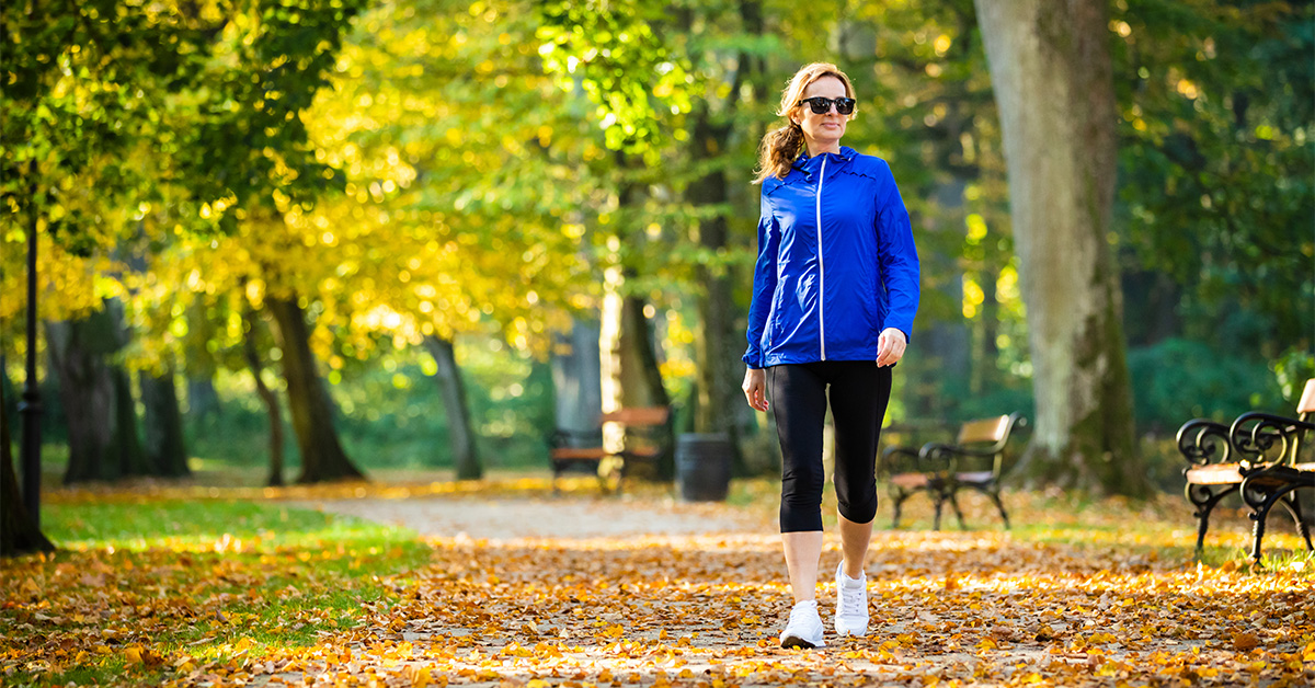 A woman wearing sunglasses walking in a park